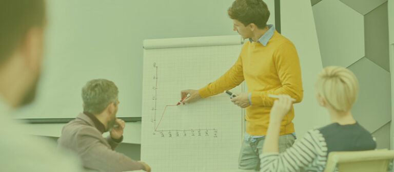 Un presentador señala un gráfico durante una reunión de negocios de endomarketing mientras sus colegas observan.